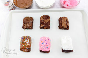 Dipping a popsicle-shaped brownie into melted pink candy melts