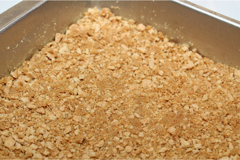 cracker crust being pressed into baking pan