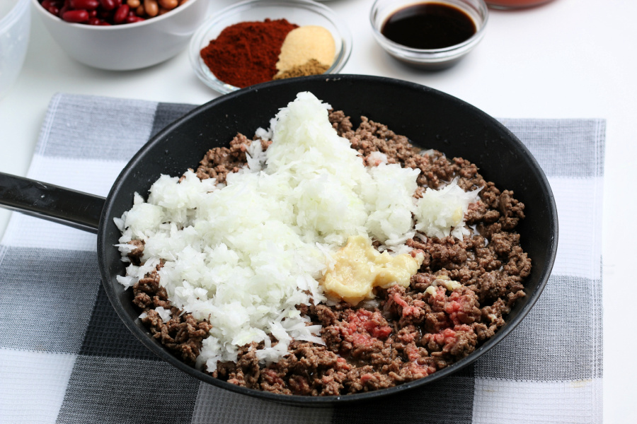 cooked ground beef, diced onion, and garlic in a frying pan