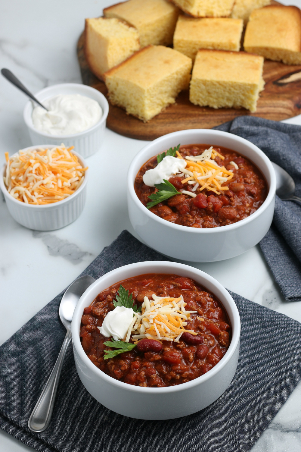 2 bowls of chili topped with shredded cheese and sour cream