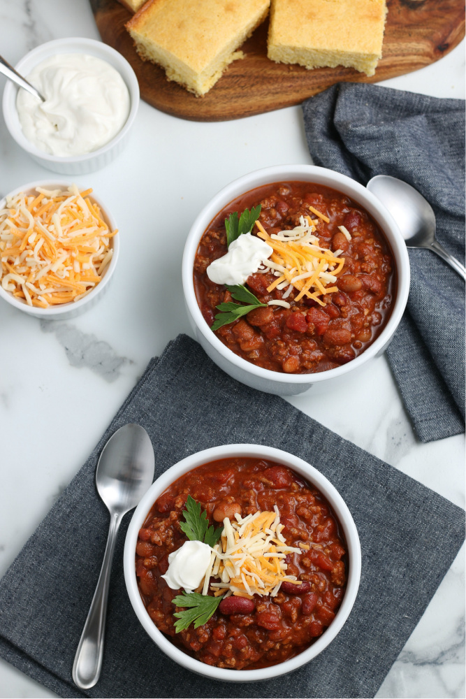 two bowls of chili with a side of corn bread