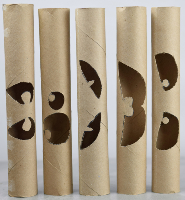 5 paper towel rolls with different eyes cut into them