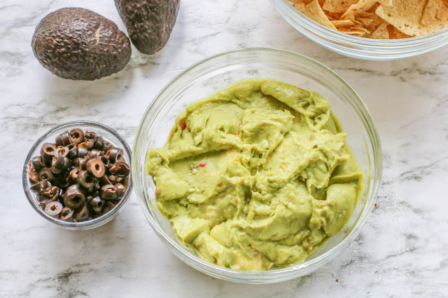 guacamole in a glass bowl and a small bowl of sliced black olives
