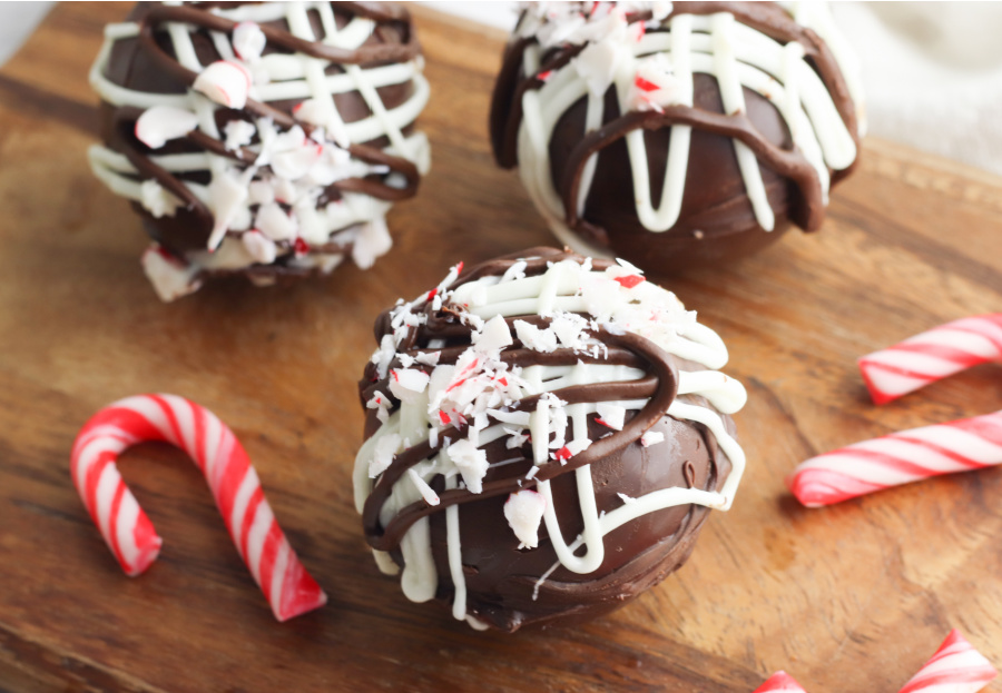 3 hot chocolate bombs on a cutting board with mini candy canes
