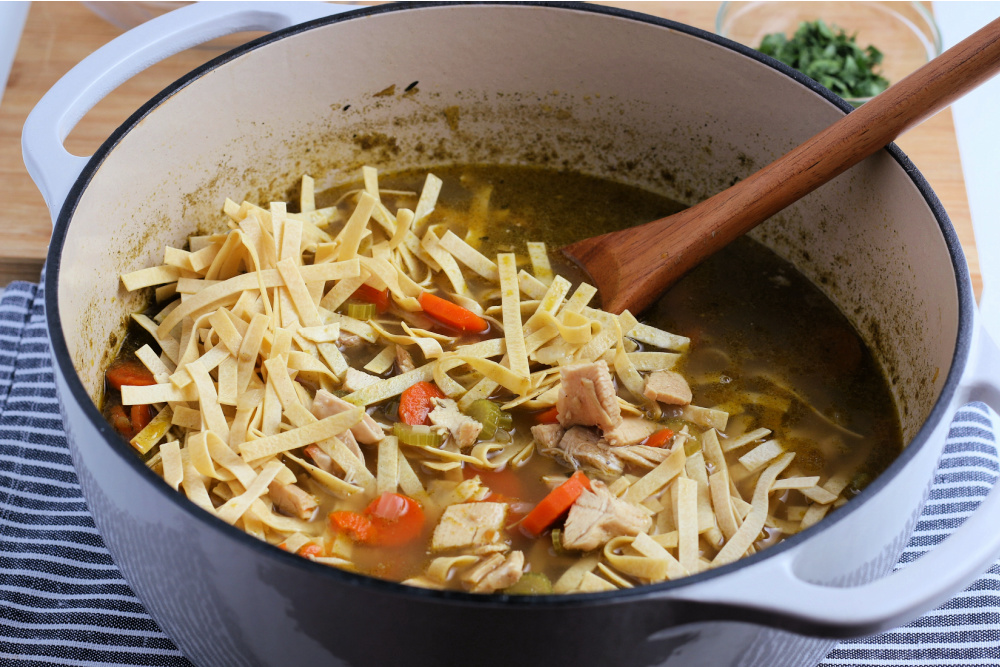 Egg noodles being added in to soup pot