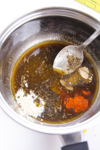 melted butter and seasoning in a cooking pot with a spoon stirring it.
