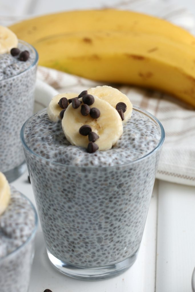 A cup of chia pudding, topped with sliced bananas and chocolate chip