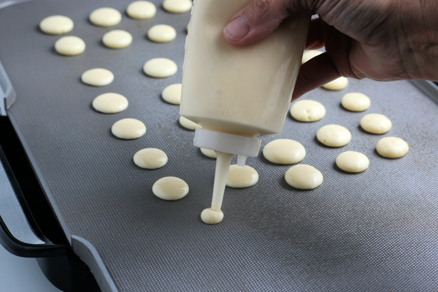squirt bottle placing dots of pancake batter on pan