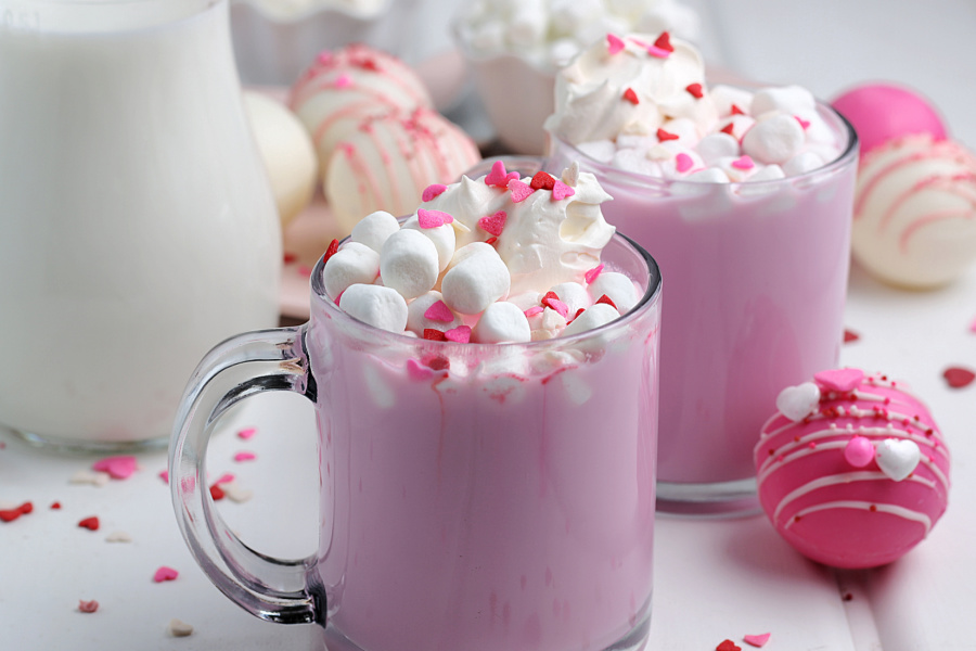 2 cups of pink hot chocolate and Valentine's Day Hot Chocolate bombs on a table