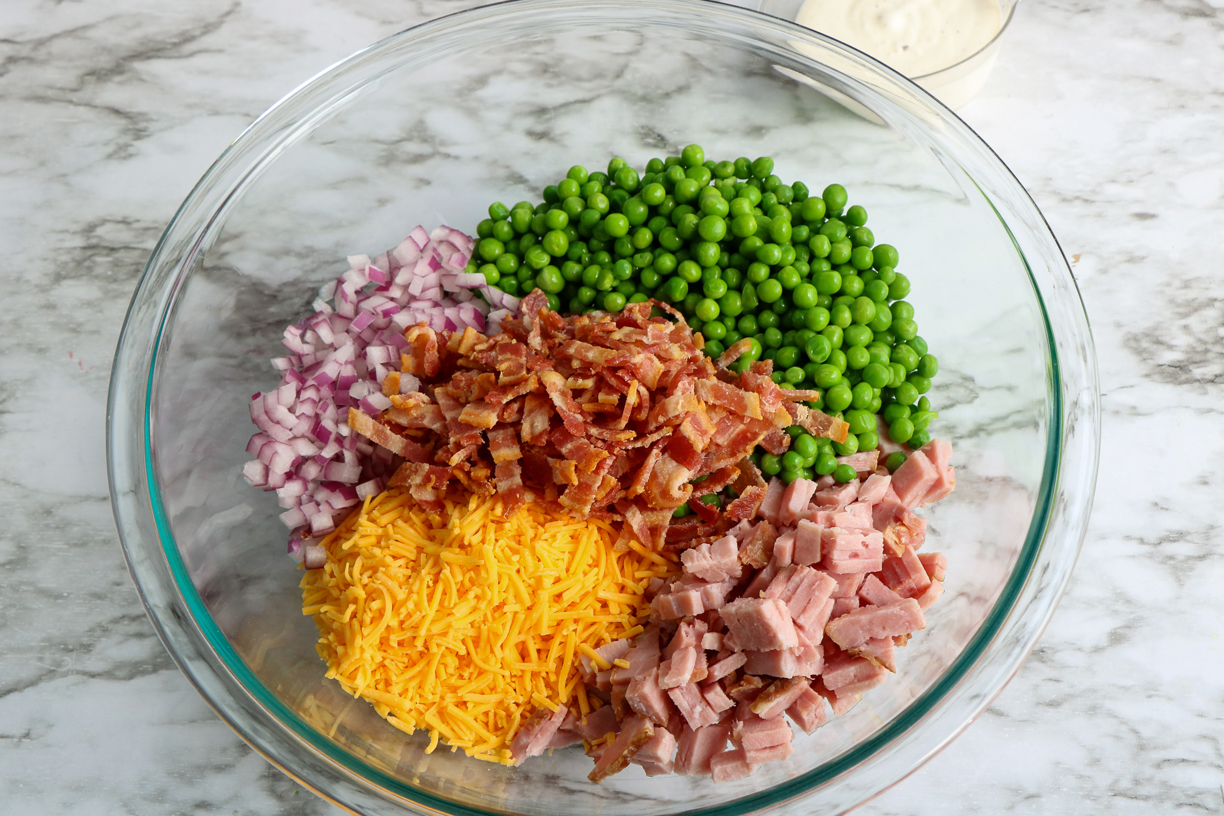 ingredients for pea salad in a large mixing bowl