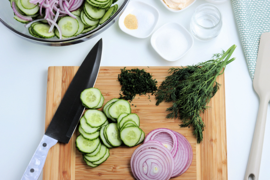 cucumber, onions and herbs chopped on a cutting board