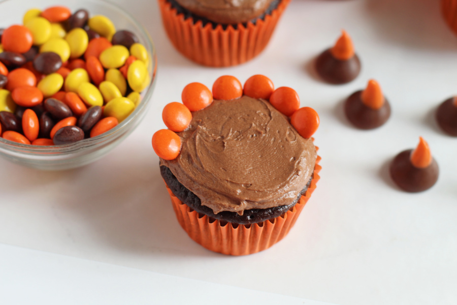 placing Reese's pieces on top of cupcake