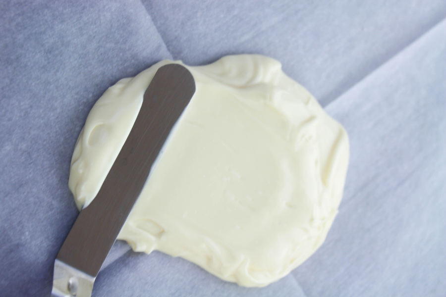 white chocolate being spread on parchment paper