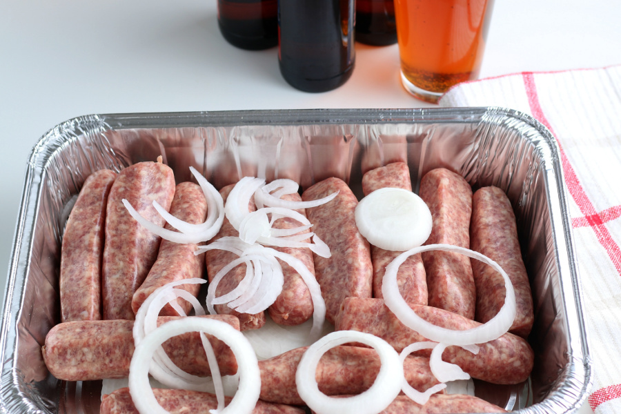 brats and sliced onion in pan