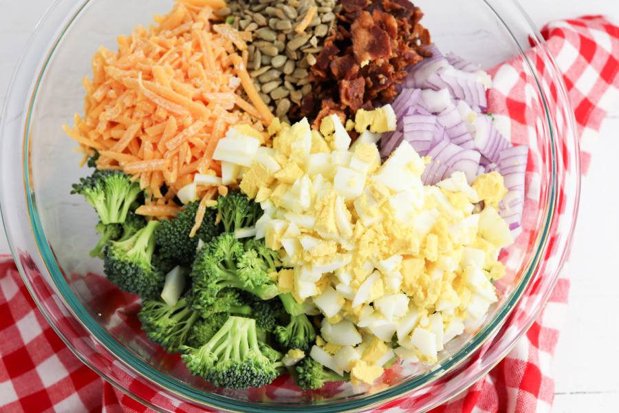 broccoli, red onion, cheddar cheese, sunflower kernels, bacon, and eggs added to bowl 
