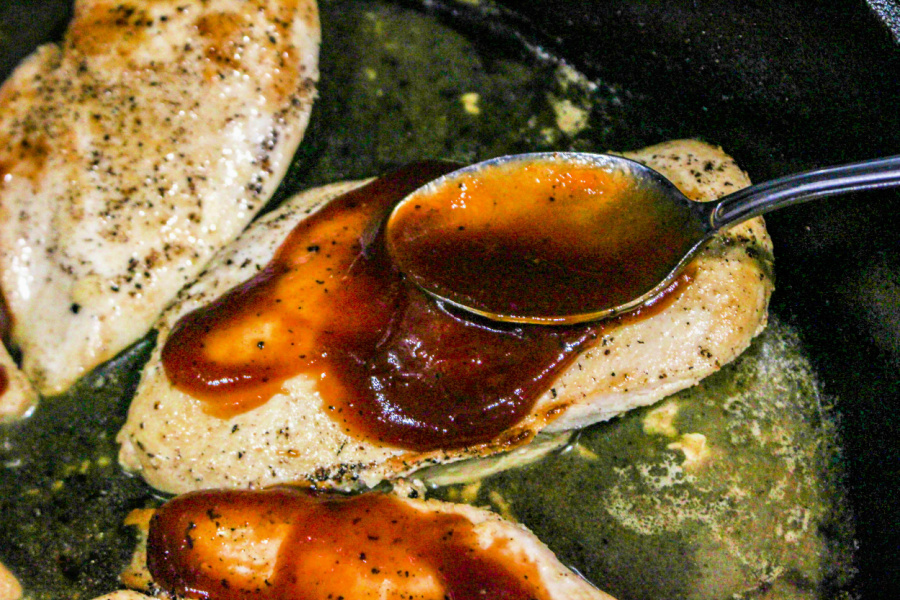 spooning bbq sauce over chicken