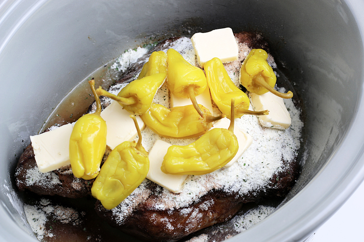 seasoning butter and peppers added to slow cooker