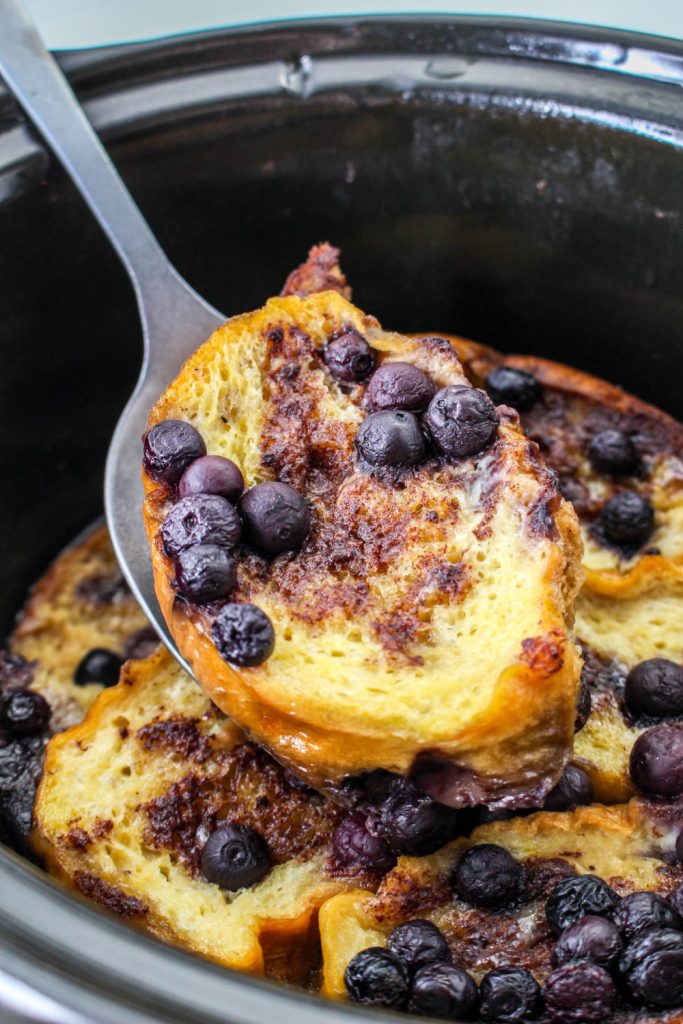 Slow Cooker Blueberry French Toast Casserole being scooped with a spoon