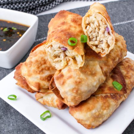 Air Fryer Chicken Egg Rolls on a plate with a side dish of sauce