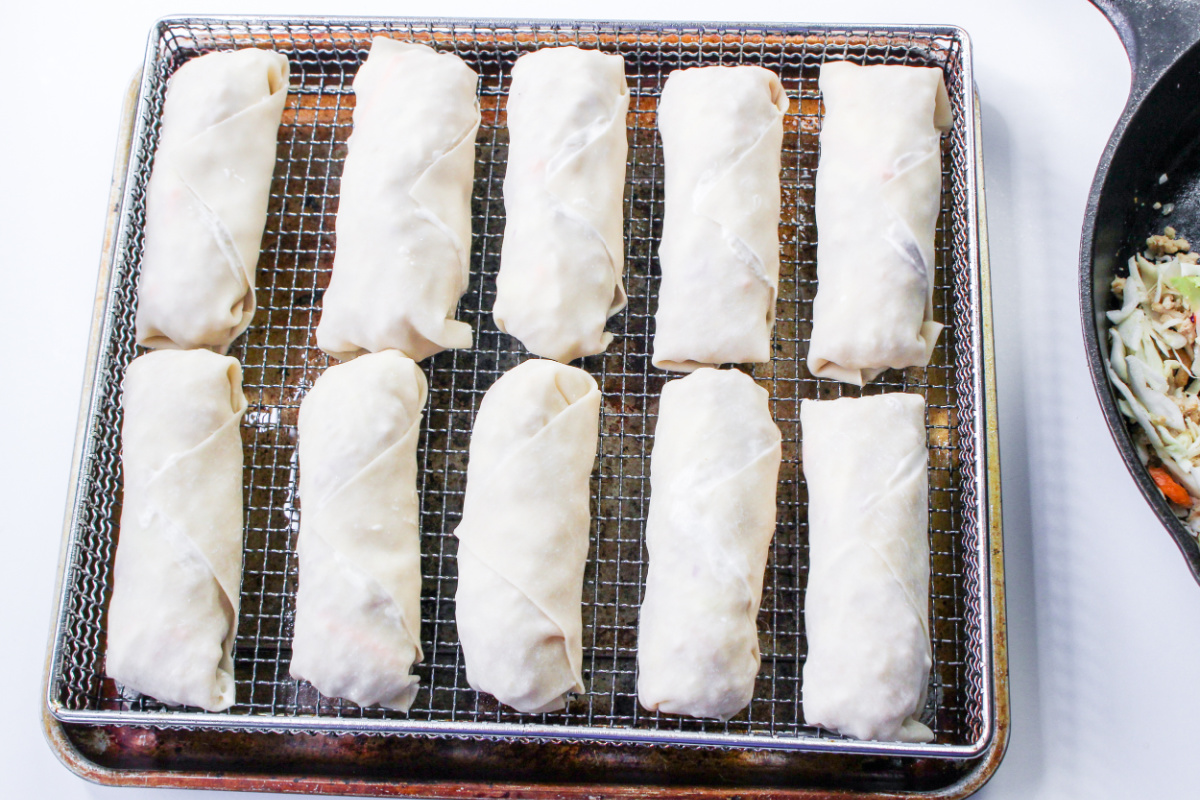 uncooked egg rolls on rack