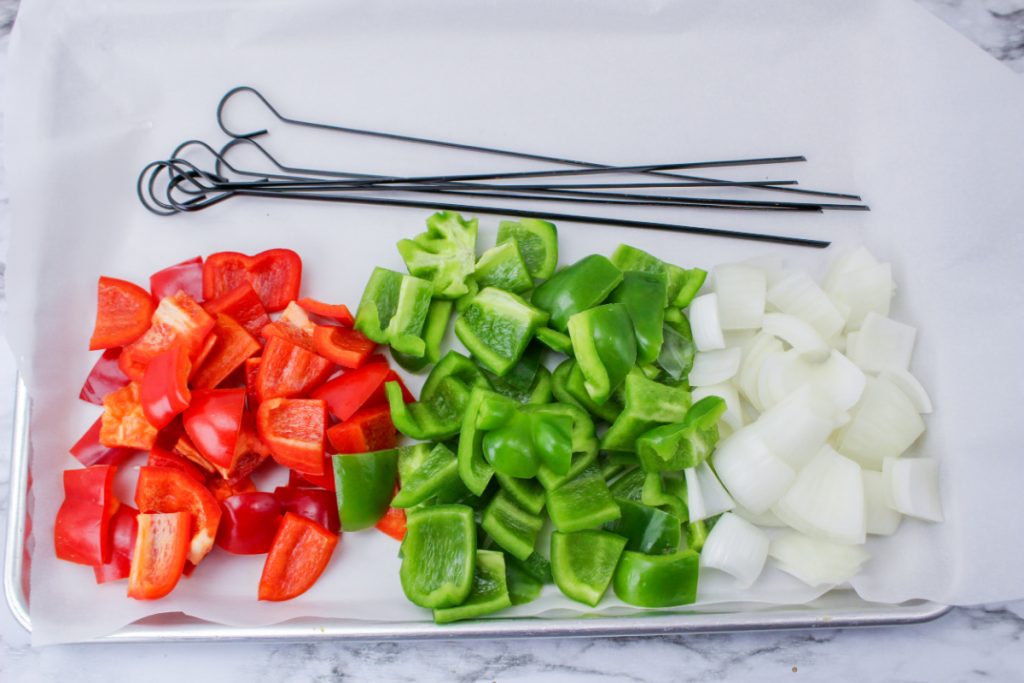 cut bell pepper and onion on a plate with skewers