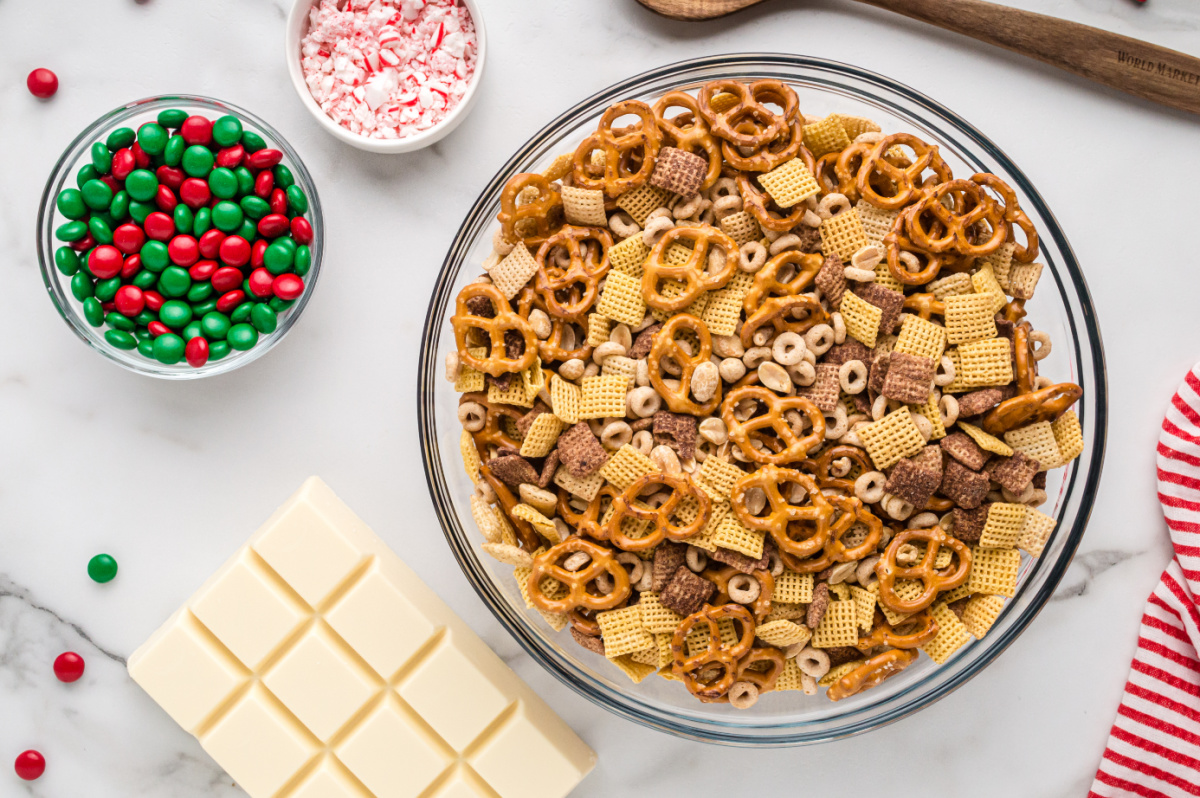 Corn Chex, Chocolate Chex, Cheerios, pretzel twists, and peanuts in a large mixing bowl