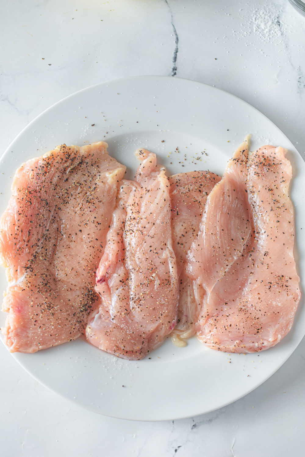 chicken breast sliced thinly on a plate with seasoning