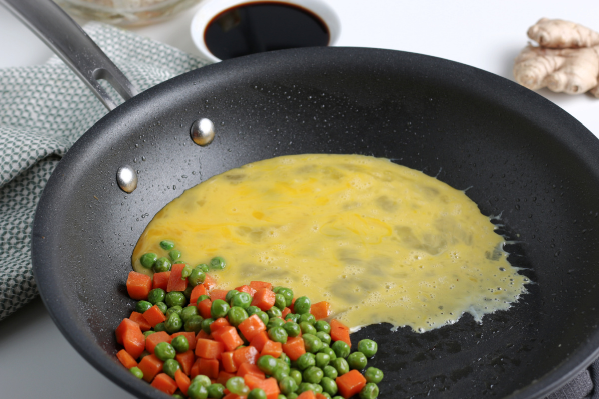 egg added to pan with peas and carrots
