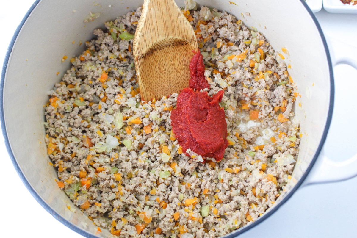 adding tomato paste to the pot