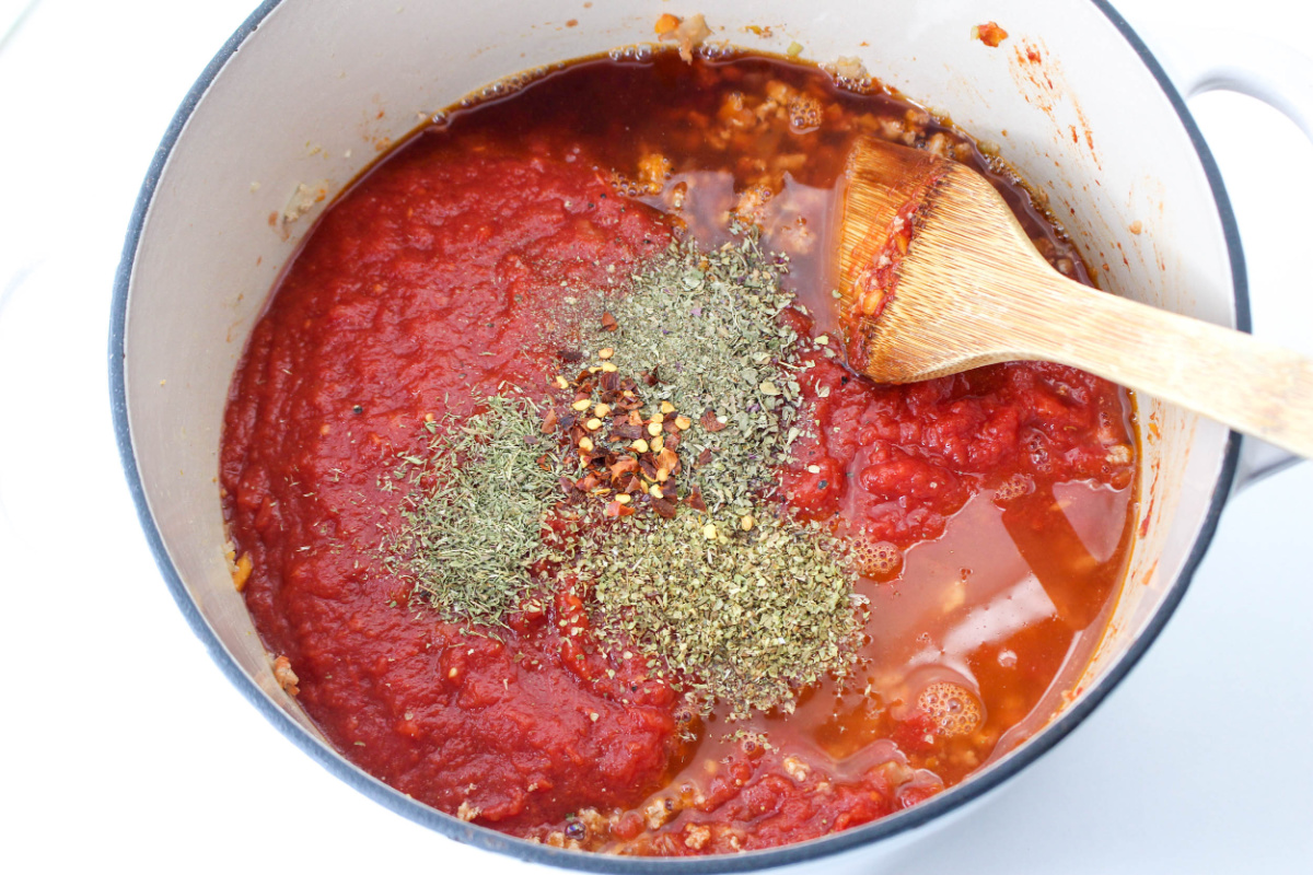 seasoning and crushed tomatoes added to pot