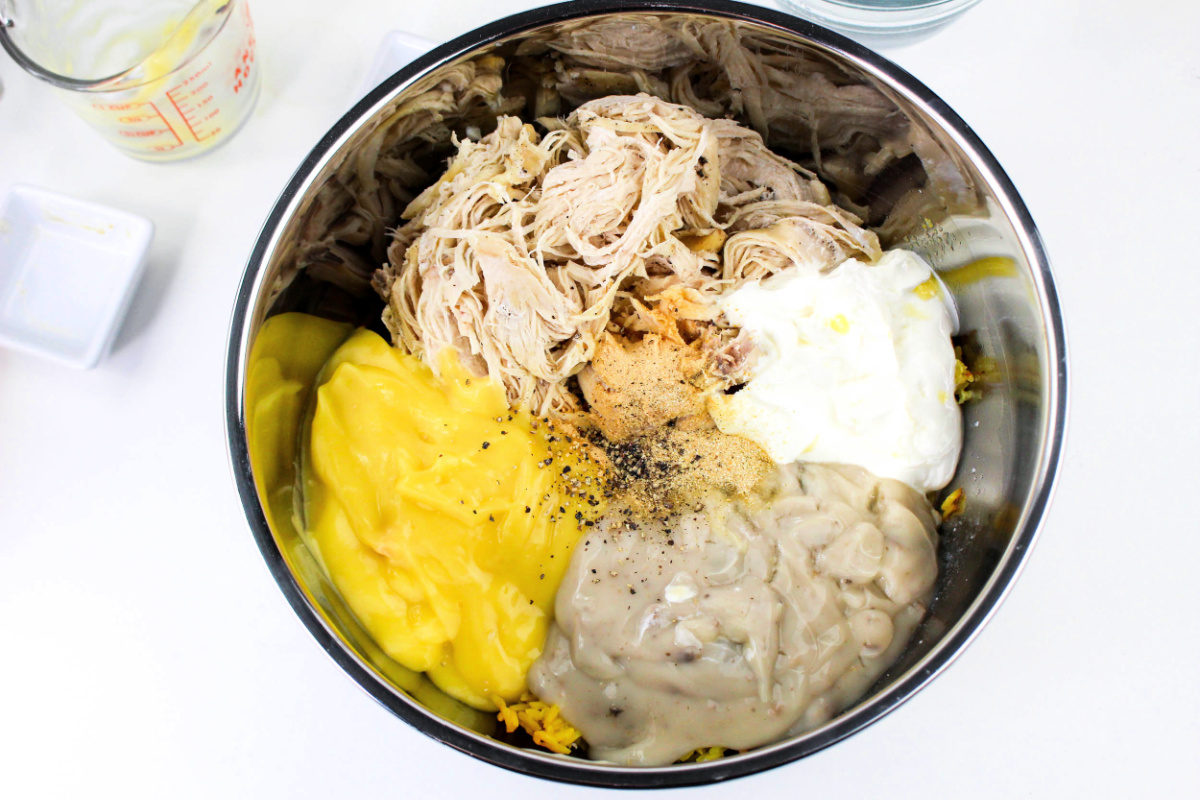 shredded chicken, soups, chicken broth, sour cream, and seasonings in a bowl