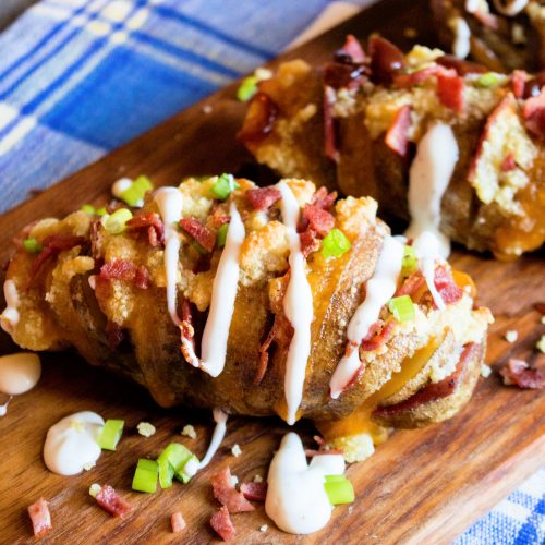 Cheesy Bacon Hasselback Potatoes on a cutting board