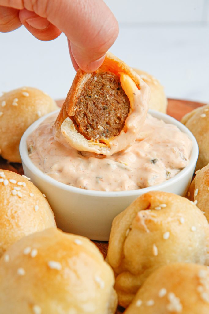 Cheeseburger Meatball Bomb being dipped in sauce