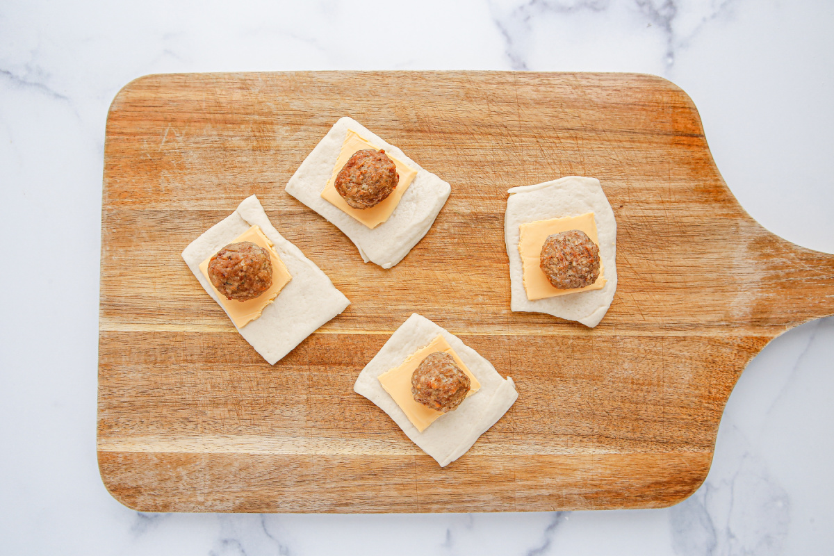 cheese slice and meatballs placed on top of dough