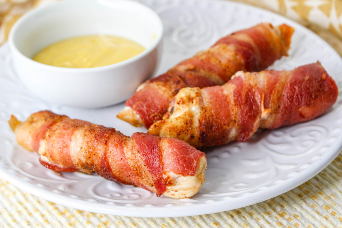 Air Fryer Bacon Wrapped Chicken Tenders on a plate with a dipping sauce