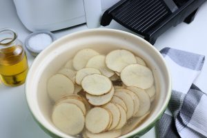 potato slices in a bowl of water