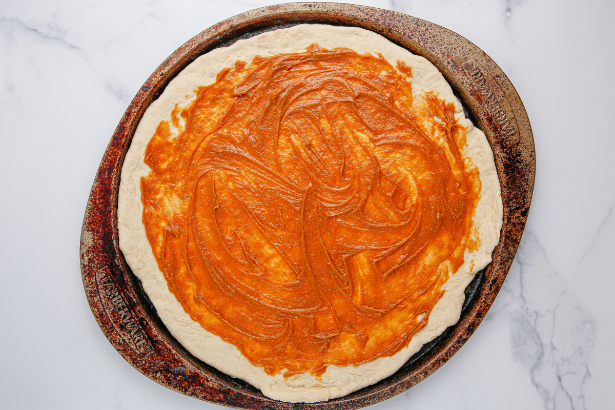 peanut sauce spread on pizza dough