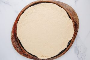 pizza dough rolled out on a pan