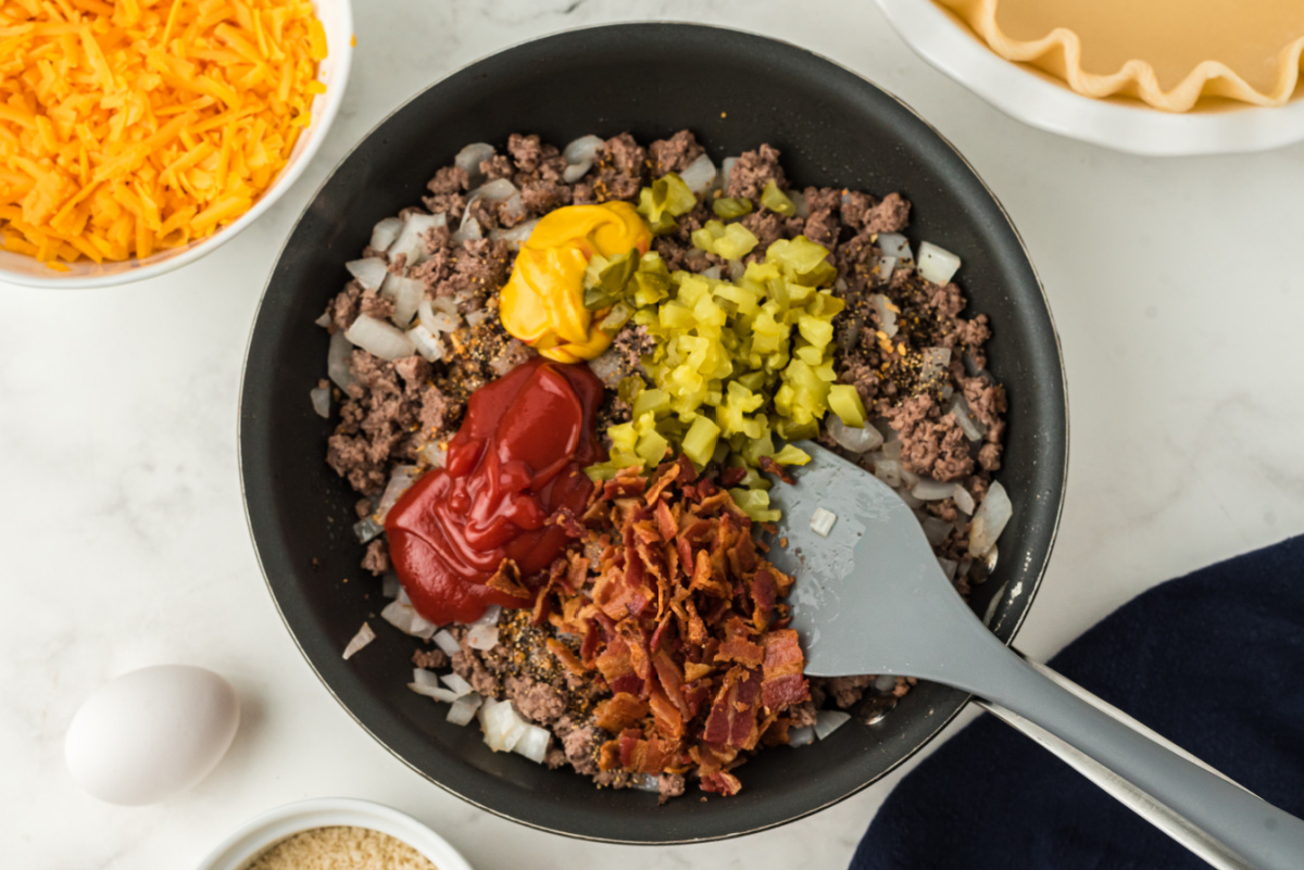 bacon, bread crumbs, mustard, ketchup, Worcestershire, pickles, and seasonings added to pan