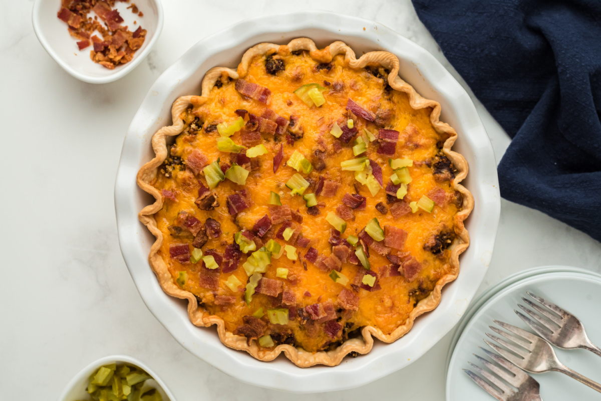 Bacon Cheeseburger Pie topped with chopped pickles and bacon
