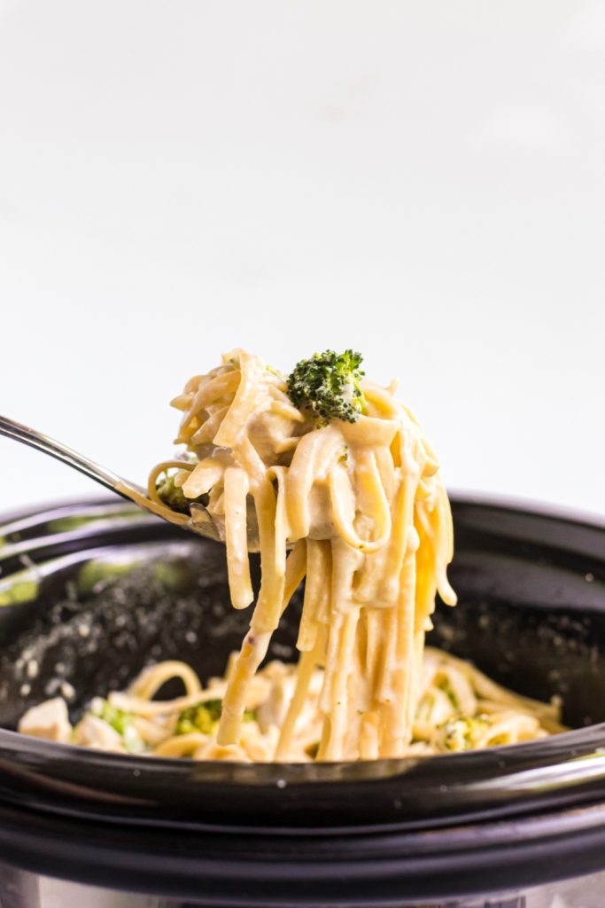 Slow Cooker Chicken Alfredo being scooped out of a slow cooker
