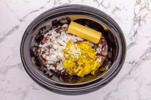onions, garlic, au jus gravy, ranch seasoning, butter, pepperoncini peppers with juice, and beef broth added to slow cooker