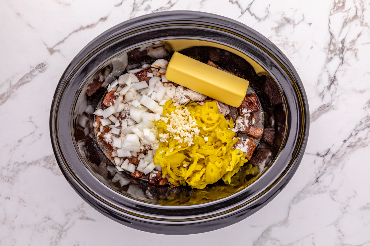 onions, garlic, au jus gravy, ranch seasoning, butter, pepperoncini peppers with juice, and beef broth added to slow cooker
