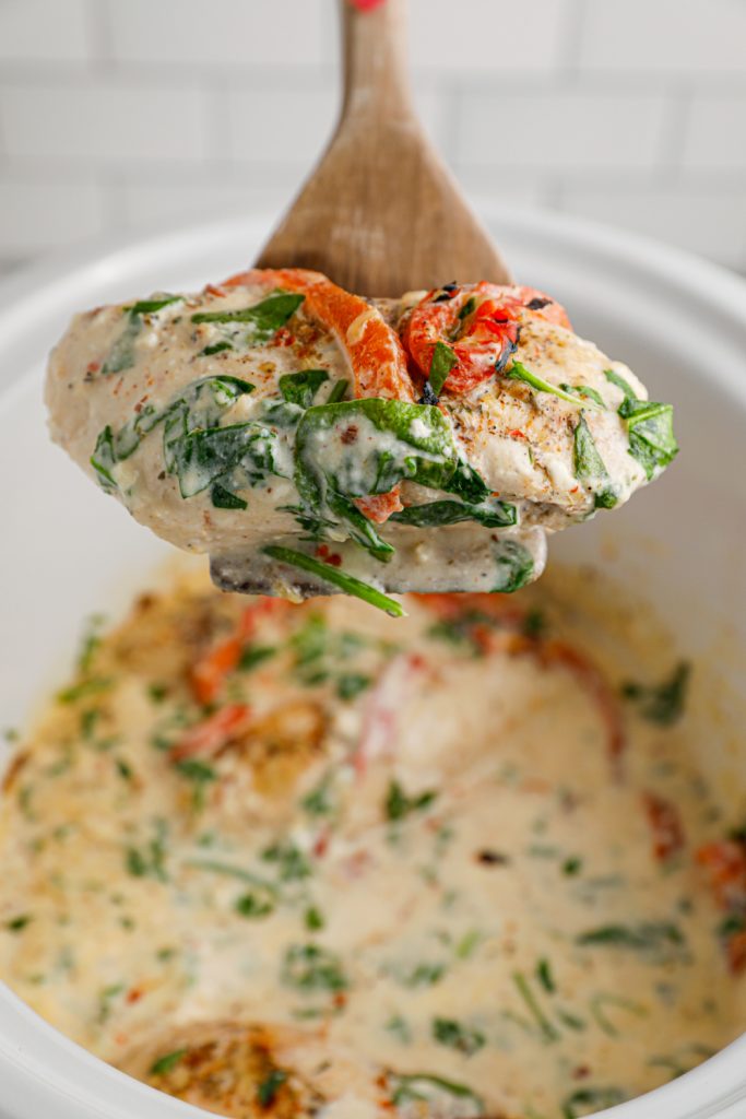 Slow Cooker Creamy Tuscan Chicken being scooped up with a spoon