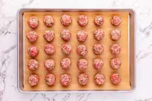 raw meatballs on a parchment paper lined baking sheet