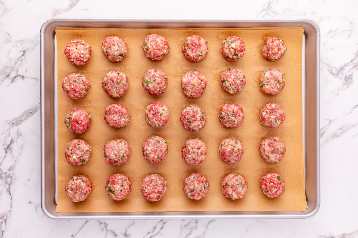 raw meatballs on a parchment paper lined baking sheet
