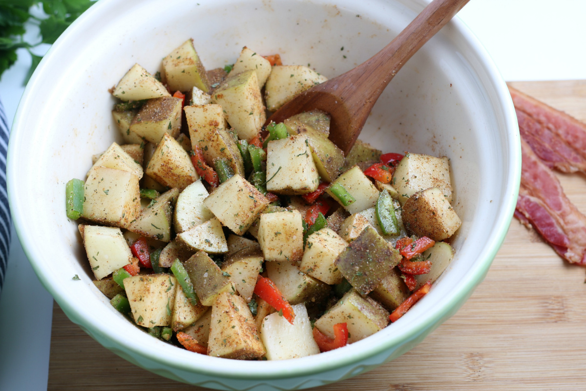 stirring potatoes and seasoning in a bowl