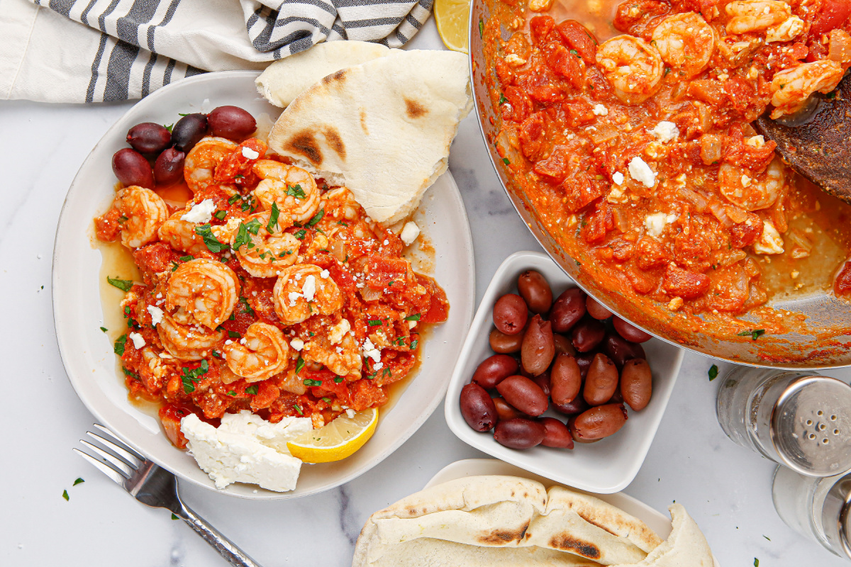 tomato feta shrimp skillet served in a bowl with pita bread and olives