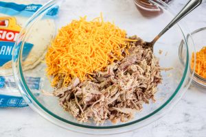 shredded cheese, and pork in a bowl