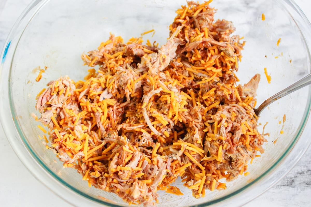 bbq sauce added in to bowl and mixed with pork and cheese